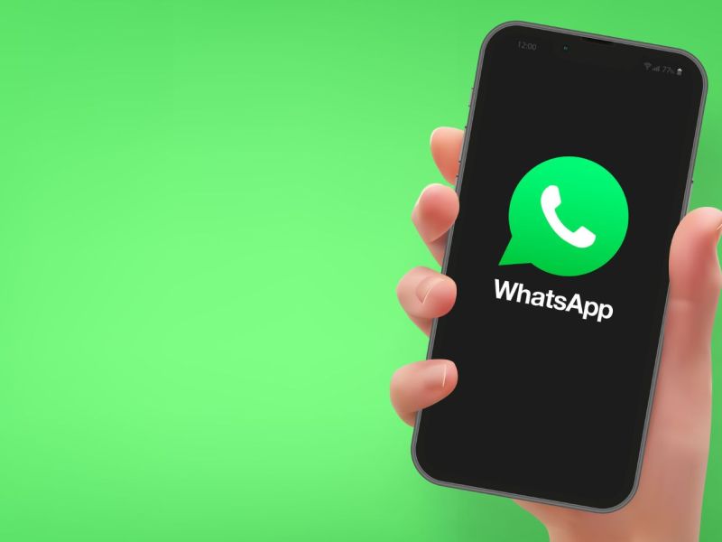 Person hält Handy mit dem WhatsApp-Logo in der Hand.