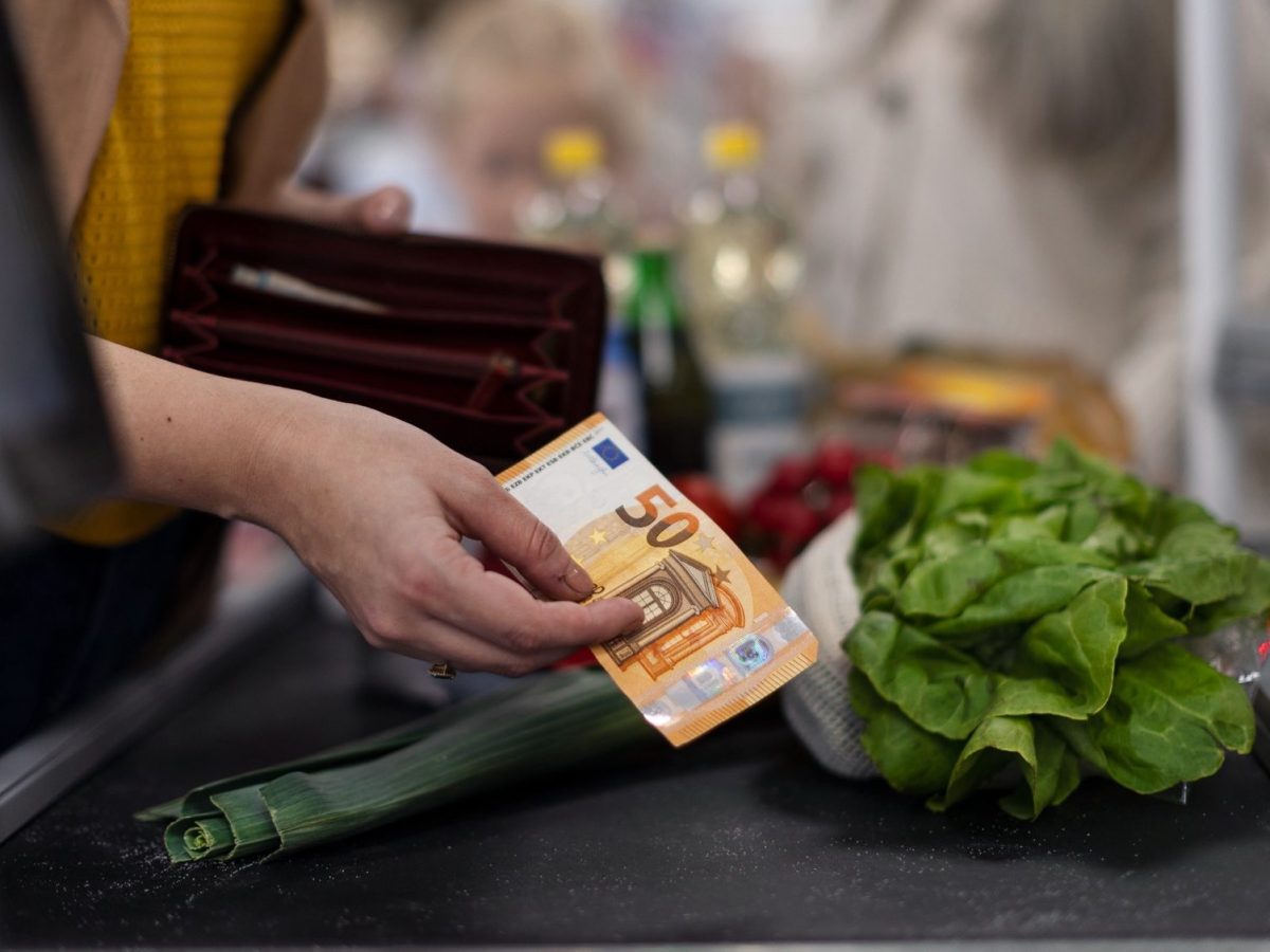 Frau bezahlt mit Bargeld an der Kasse