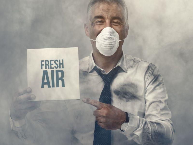 Mann mit Atemmaske im Gesicht hält ein Schild hoch mit der Aufschrift: "Fresh Air".