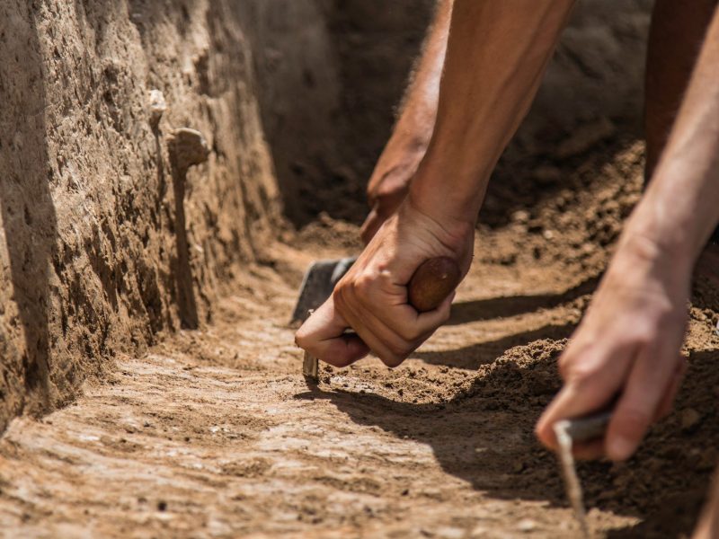 HÃ¤nde graben mit Werkzeugen an archÃ¤ologischem Fund.