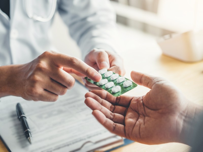 Person übergibt einer anderen eine Tabletten-Packung