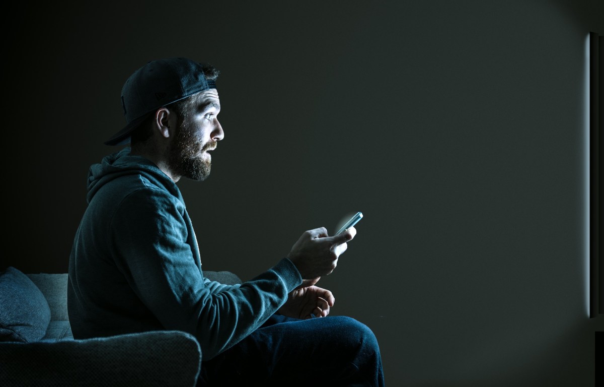 Mann sitzt im Dunkeln vor dem Fernseher