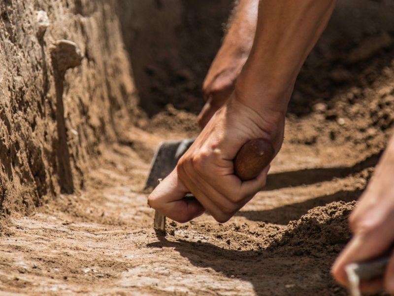 HÃ¤nde graben mit Werkzeugen an einem archÃ¤ologischen Fund.