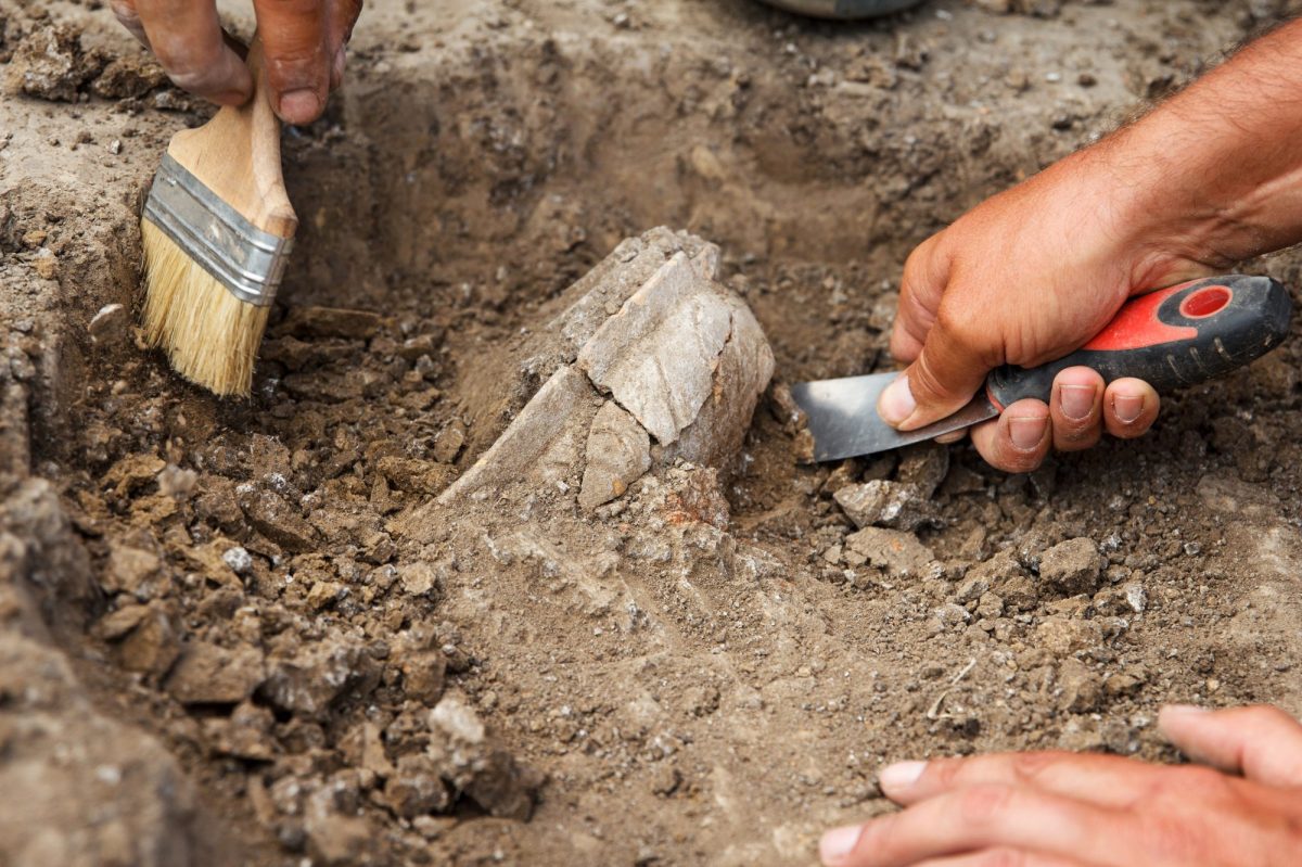 HÃ¤nde graben mit Werkzeugen an einem archÃ¤ologischen Fund.