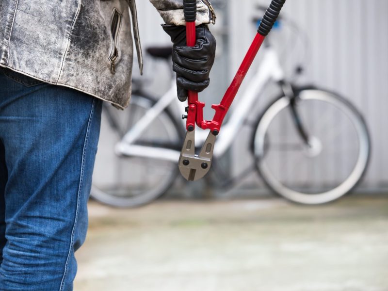 Person hÃ¤lt eine Zange. Im Hintergrund steht ein Fahrrad an einer Wand.