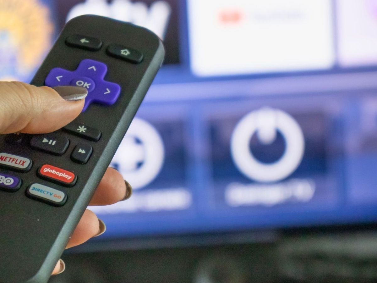 Roku-Fernbedienung mit Streaming-Bildschirm im Hintergrund.