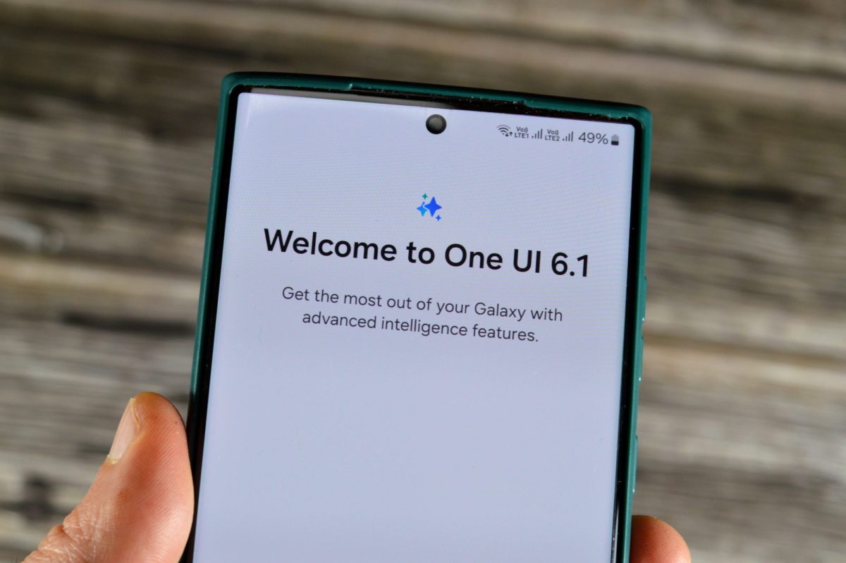 Person hält ein Samsung Galaxy in der Hand. Auf dem Display steht "Welcome to One UI 6.1"