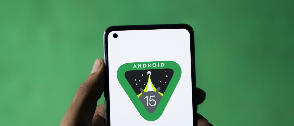 Hand hält Smartphone in der Hand, auf dem Bildschirm ist das Android 15-Logo zu sehen.