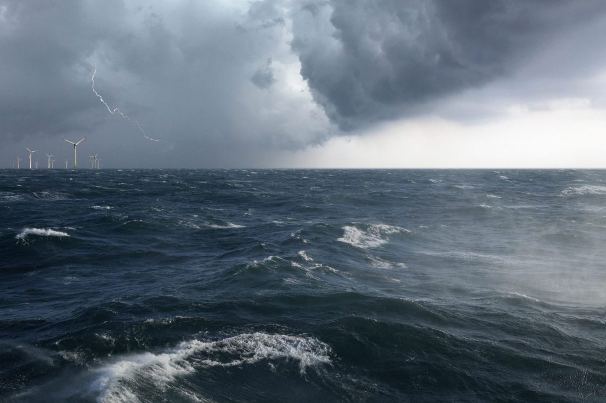 Ein Offshore Windpark mit aufgewühlter See in einem Sturm mit Blitz.