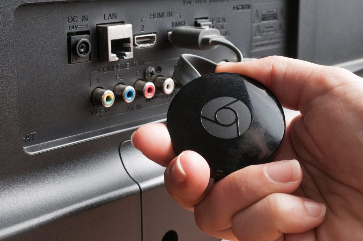 Eine Person schließt einen Chromecast TV-Stick an einen Fernseher an.