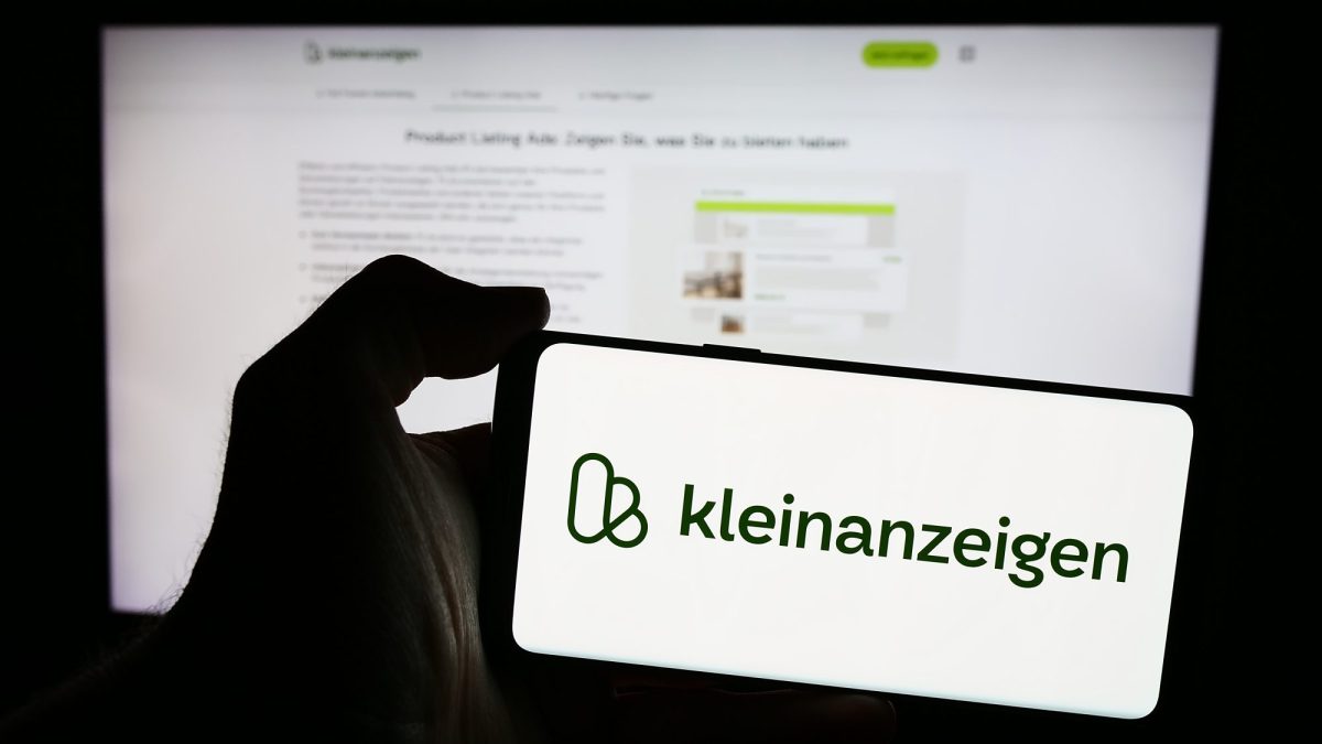 Person hÃ¤lt ein Smartphone in der Hand, auf dem Bildschirm ist das Logo von Kleinanzeigen zu sehen,