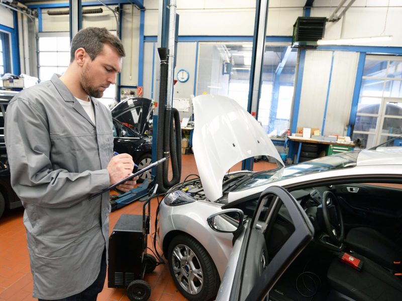 TÃœV-PrÃ¼fer steht an einem Auto.