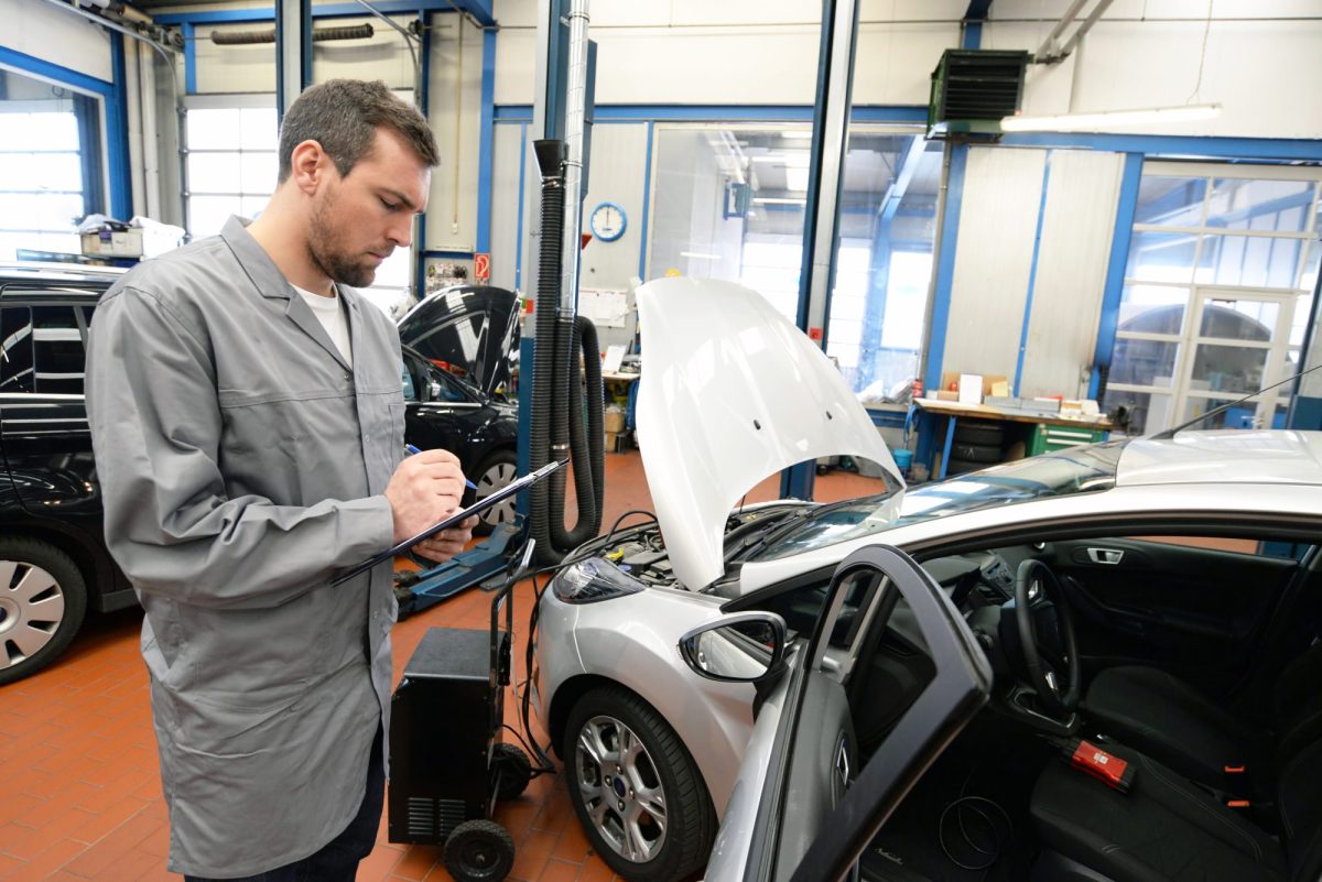 TÃœV-PrÃ¼fer steht an einem Auto.