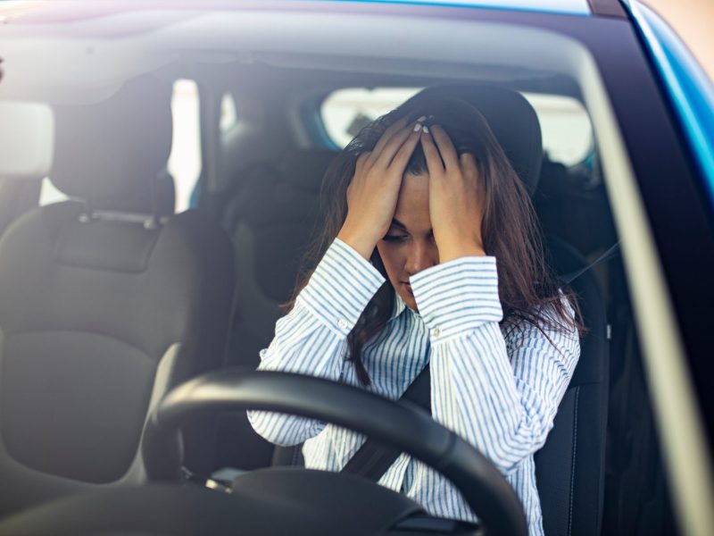 Verzweifelte Person hÃ¤lt sich im Auto die HÃ¤nde vors Gesicht.