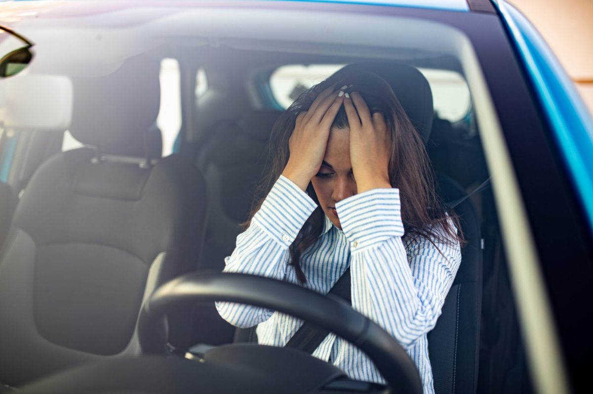 Verzweifelte Person hÃ¤lt sich im Auto die HÃ¤nde vors Gesicht.