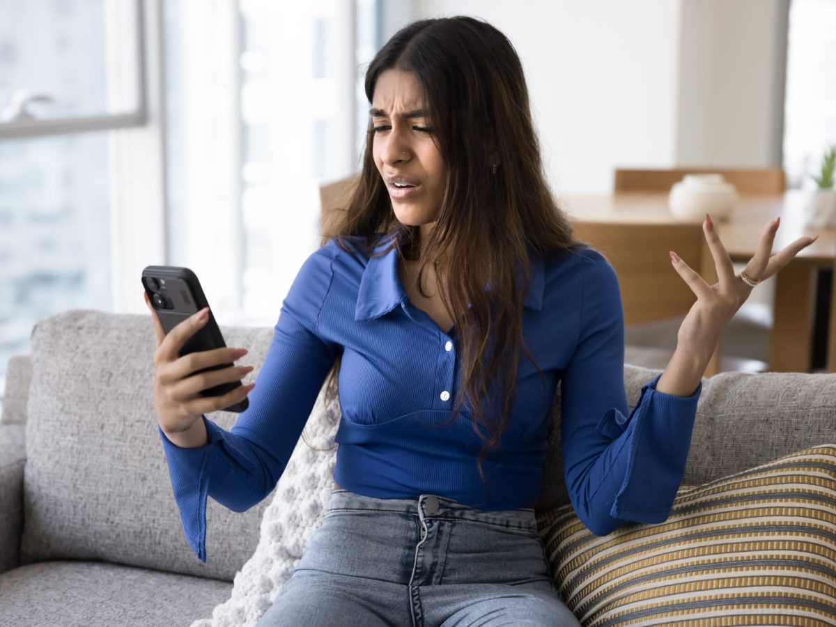 Frau hÃ¤lt Handy in der Hand und macht eine Geste der UnverstÃ¤ndnis.