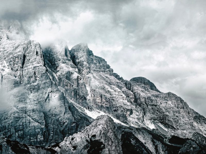 Von Schnee bedeckte Berglandschafr, die von Nebel umgeben ist.