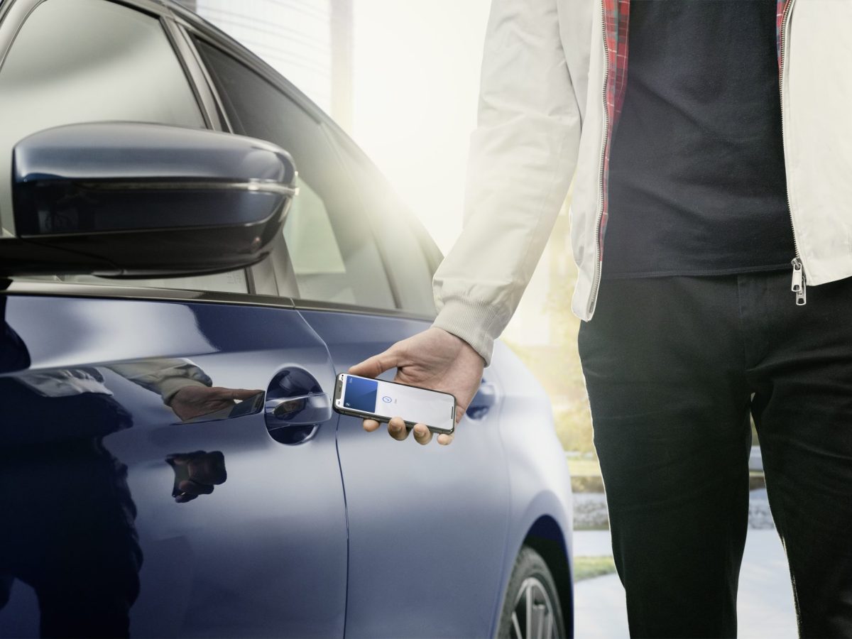 Person Ã¶ffnet Auto mit dem Apple Car Key.