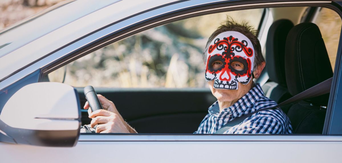 Man mit Halloween-Maske im Auto.