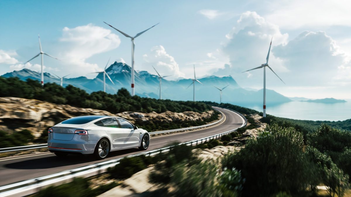 Elektroauto auf einer Autobahn mit WindrÃ¤dern im Hintergrund.