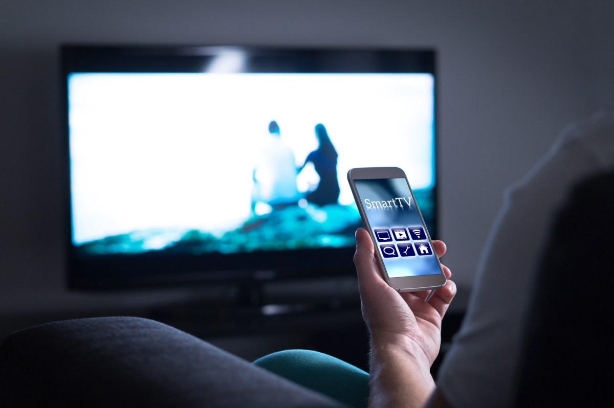 Person hÃ¤lt ein Smartphone vor einen Fernseher