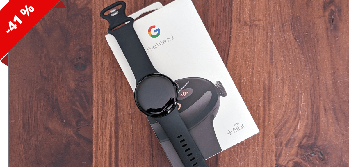 Google Pixel Watch 2 liegt auf einem Karton, der auf einer Unterlage aus Holz liegt,