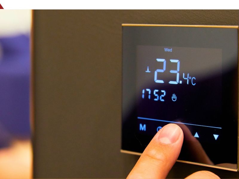 Person bedient ein Raumthermostat