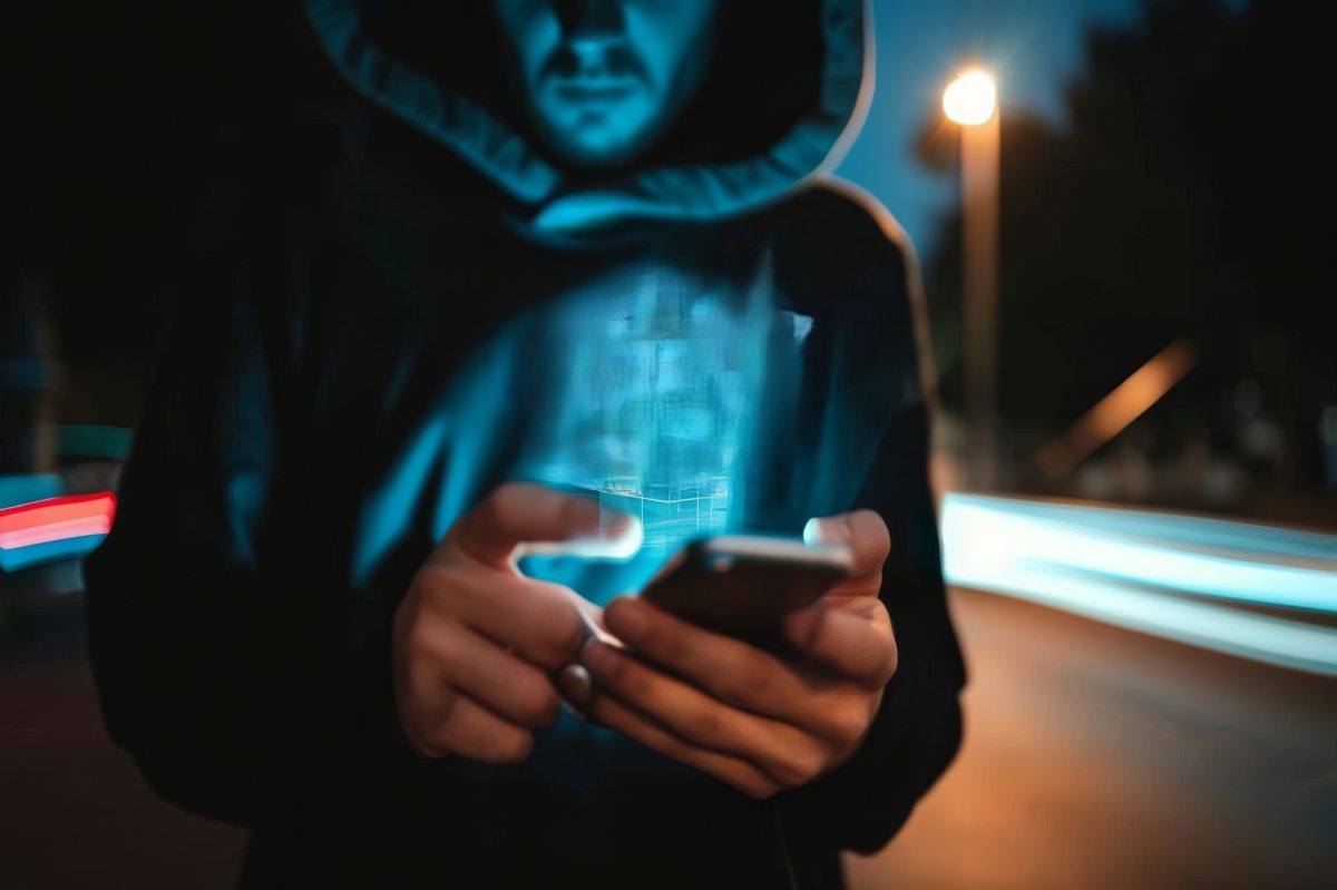 Person mit Kapuze Ã¼berm Kopf hÃ¤lt ein Handy in der Hand.