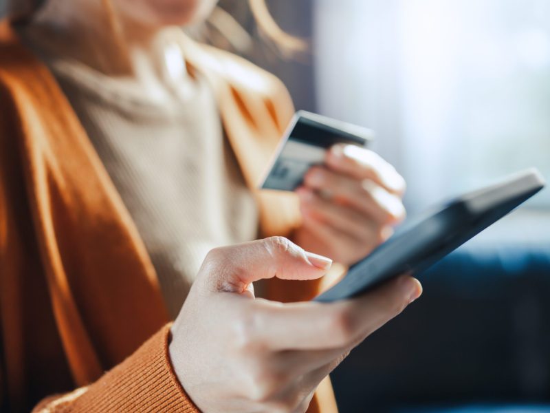 Eine Person hÃ¤lt in der einen Hand ein Handy und in der anderen Hand eine Bankkarte