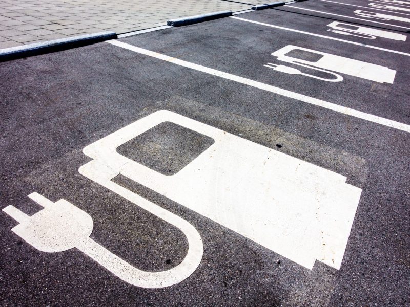 Symbol einer Ladesäule für Elektroautos ist auf den Straßenbelag gezeichnet.
