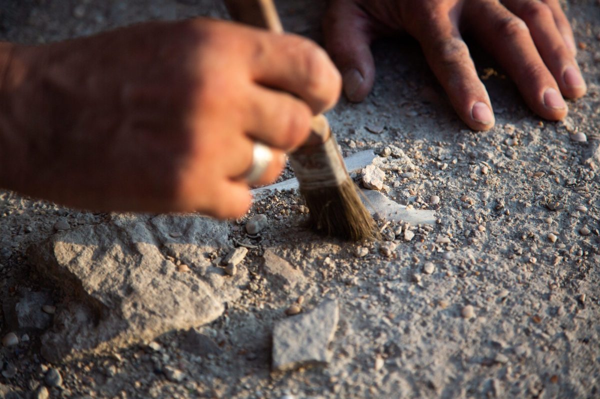 Person legt einen archäologischen Fund mit einem Pinsel frei. (Symbolbild)