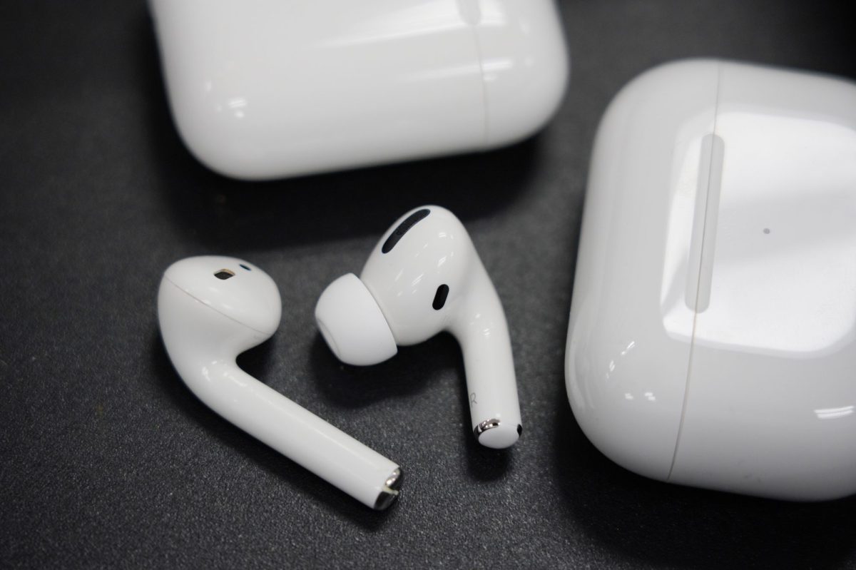 AirPods neben Lade-Case auf schwarzem Untergrund.