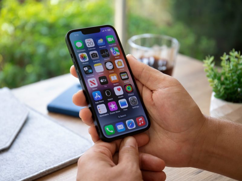 Person hält ein eingeschaltetes iPhone in der Hand.