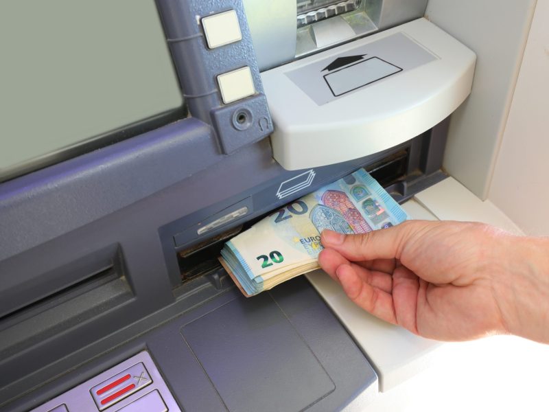 Person hebt Bargeld an einem Bankautomaten ab.
