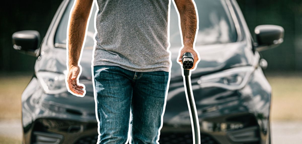 Mann mit Ladekabel vor einem Elektroauto
