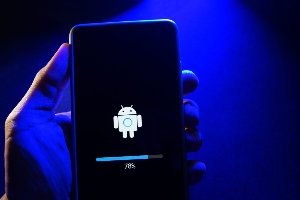 Person hält ein Handy in der Hand, auf dem ein neues Android-Update geladen wird.