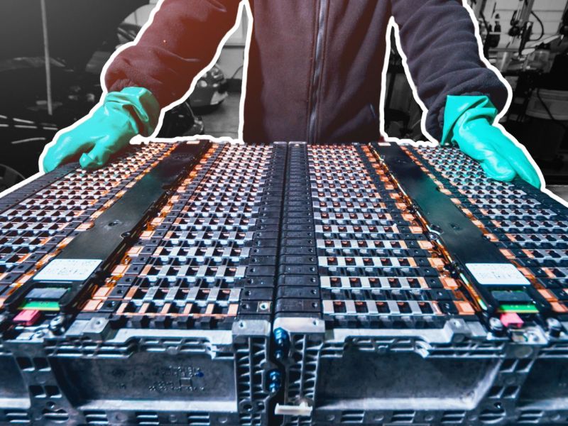 Person steht bei der Batterie eines Elektroautos