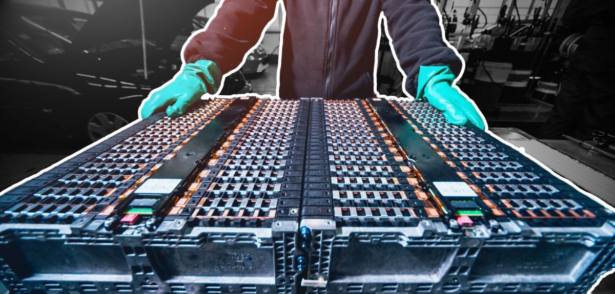 Person steht bei der Batterie eines Elektroautos