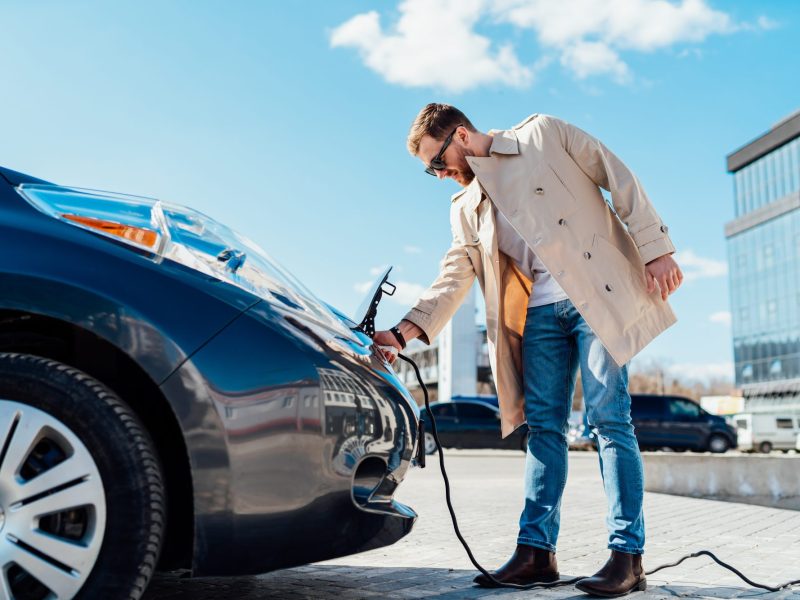 Ein Mann lädt ein Elektroauto.