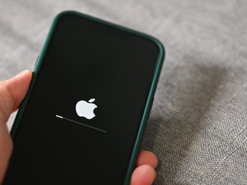 Person hält ein iPhone in der Hand, auf dem gerade ein Update lädt.