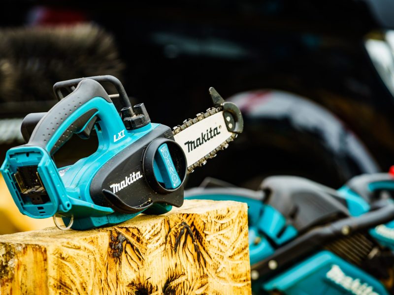 Makita-Akku-Kettensäge auf einem Holzblock.