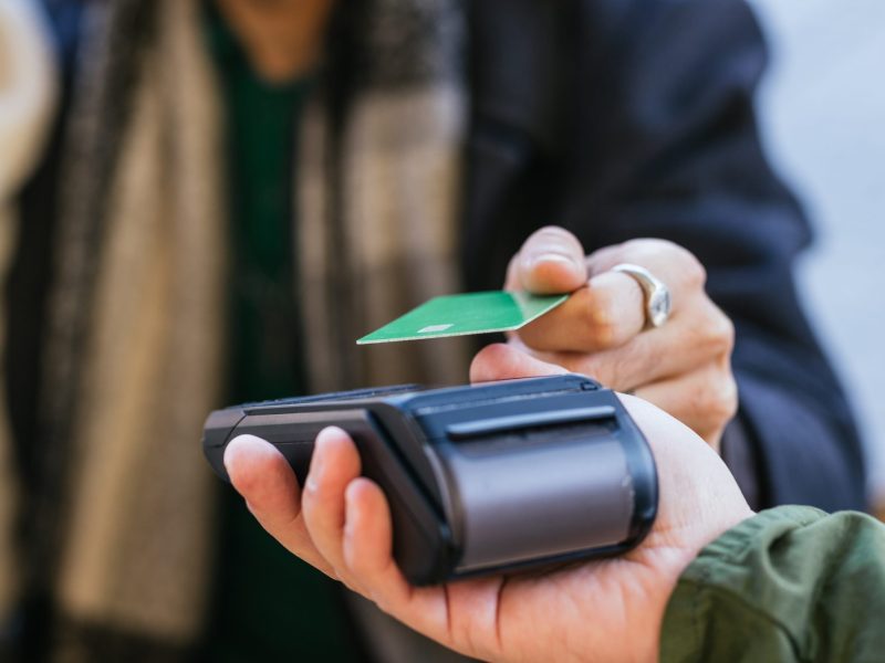 Eine Person hält eine Bankkarte an ein Kartenlesegerät.
