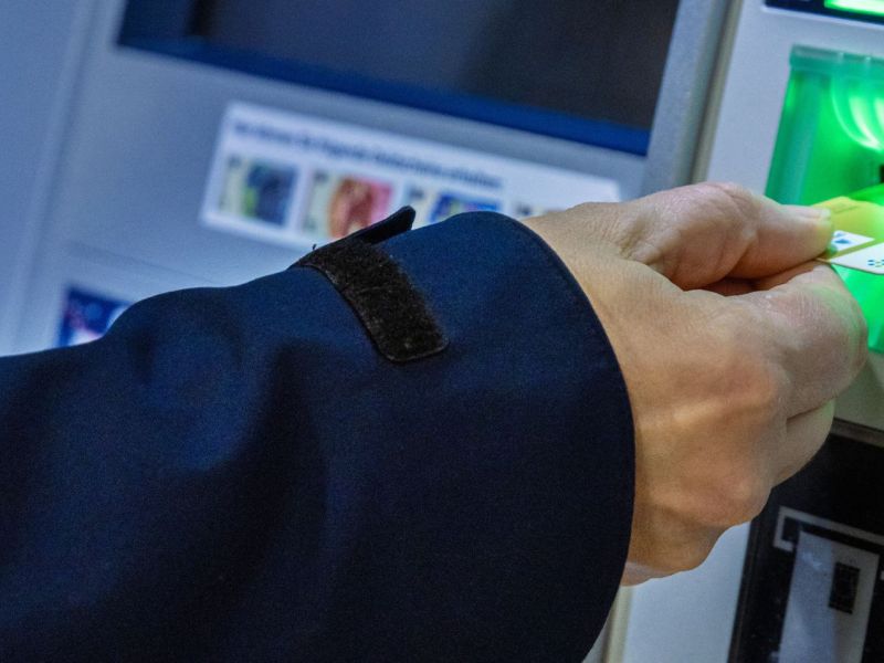 Person gibt eine Bankkarte in einen Bankautomaten ein.