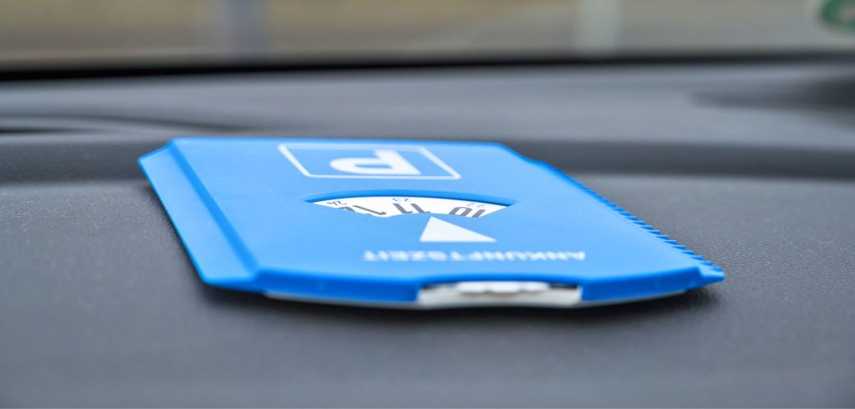 Blaue Parkscheibe liegt auf dem Armaturenbrett eines Autos