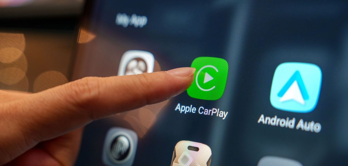 Person tippt mit dem Zeigefinger auf die Apple Carplay-App auf einem Display.