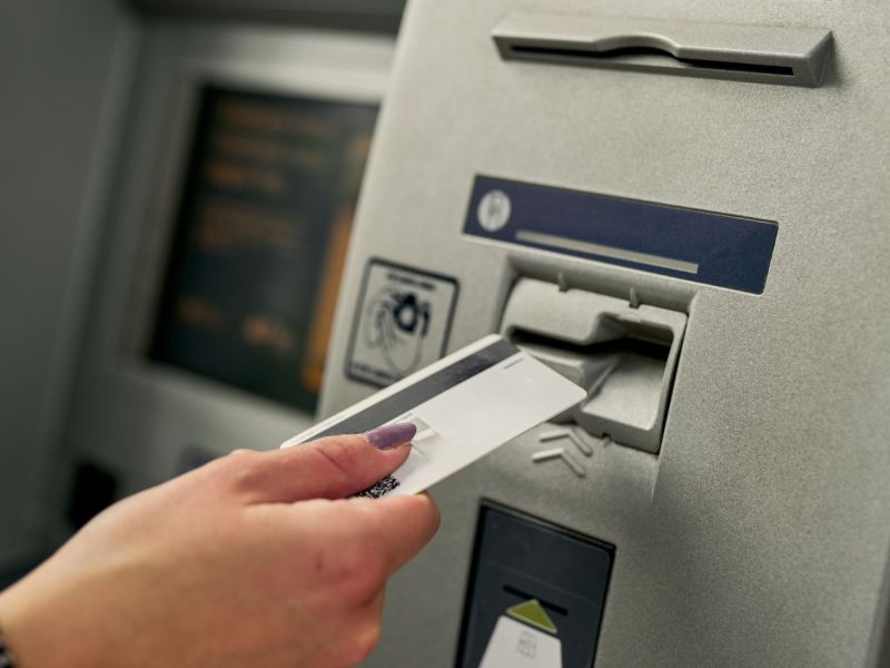 Person steckt eine Karte in einen Bankautomaten