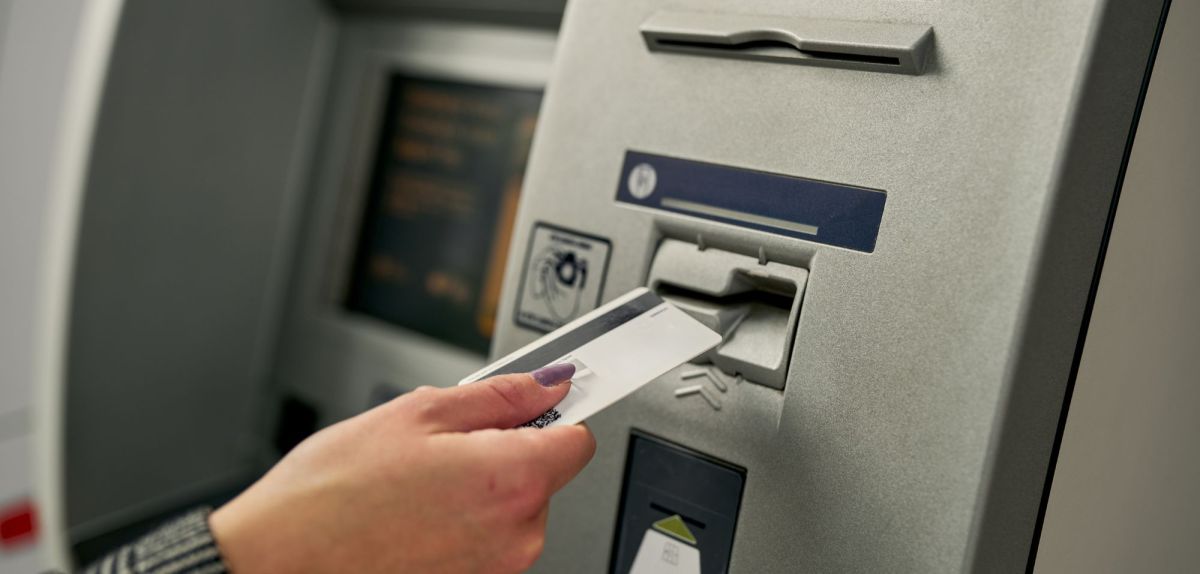 Person steckt eine Karte in einen Bankautomaten