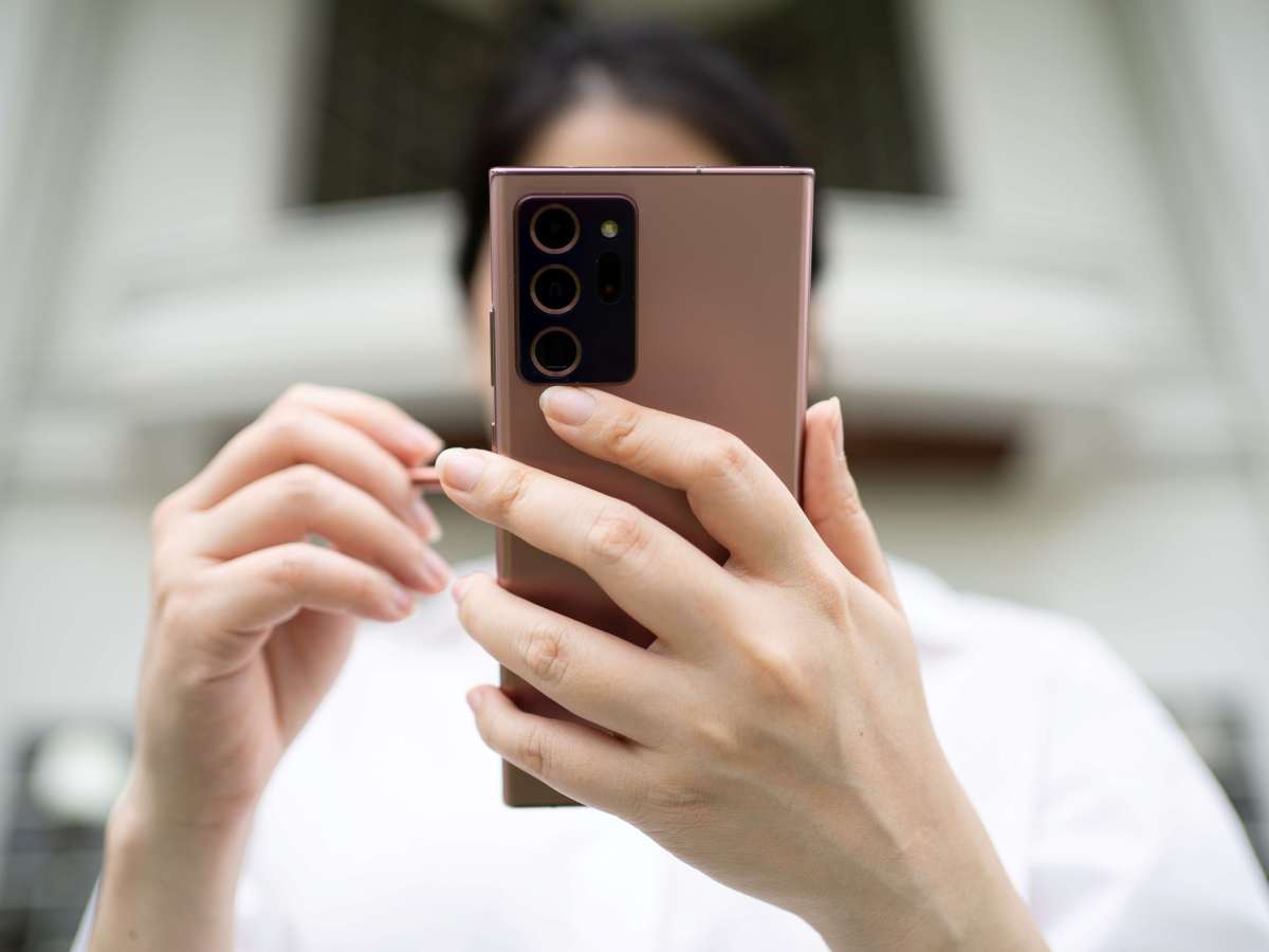Person hält Smartphone in der Hand und tippt auf das Display des Handys.