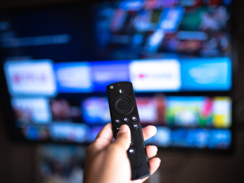 Fire TV-Stick mit Fernseher im Hintergrund