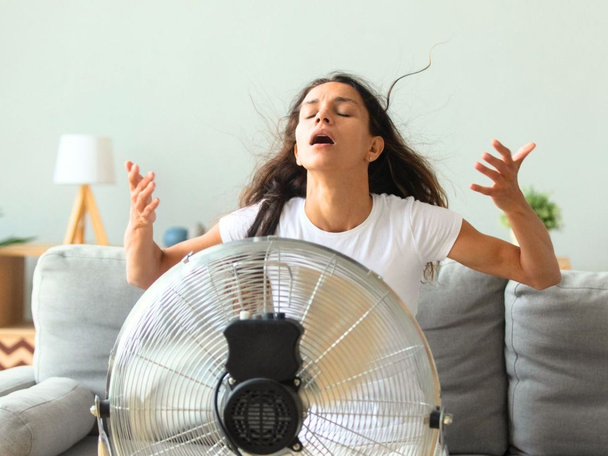 Frau kühlt sich mit einem Ventilator ab.